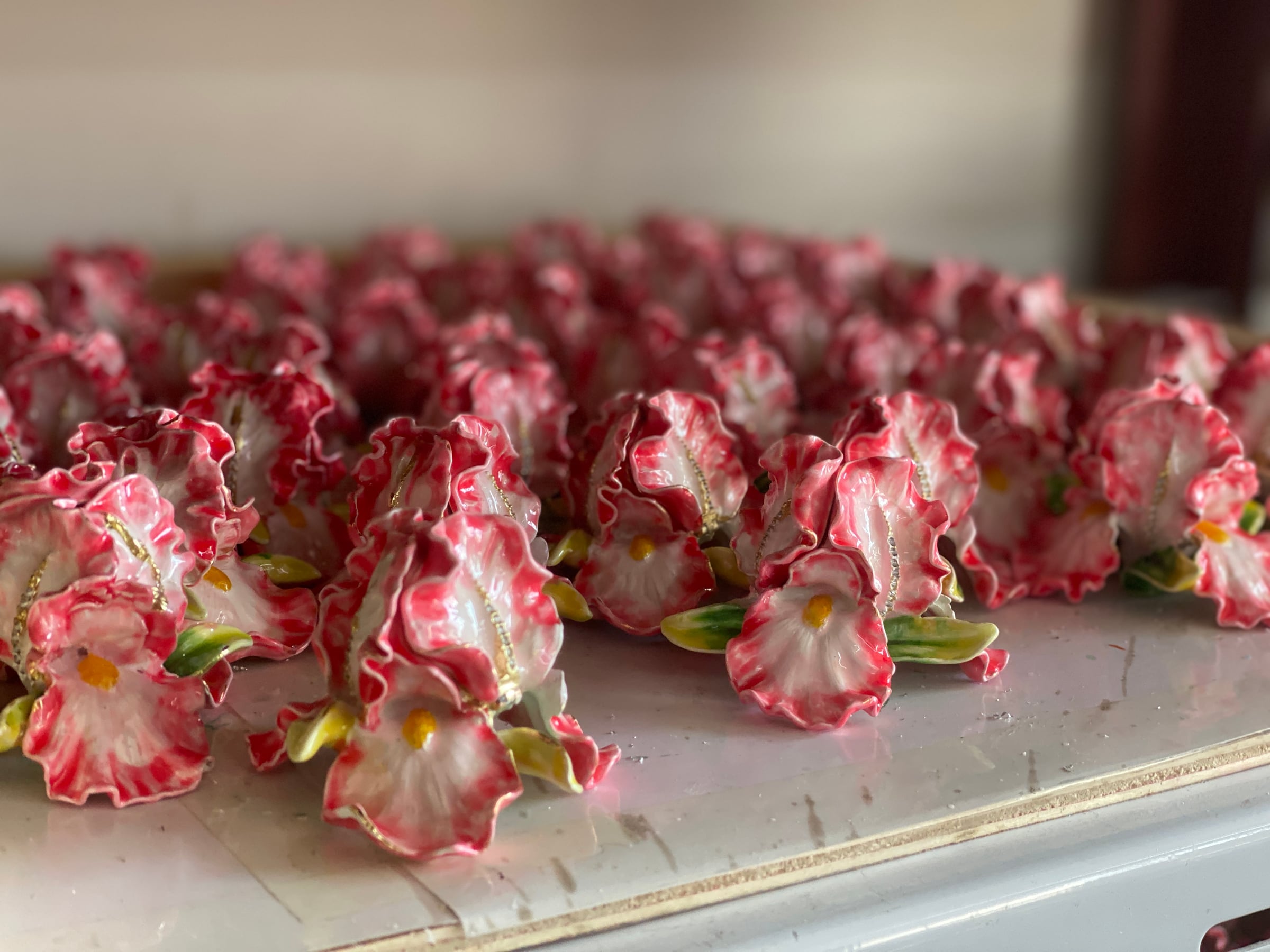 Batches of hand-finished floral enamel components in production
