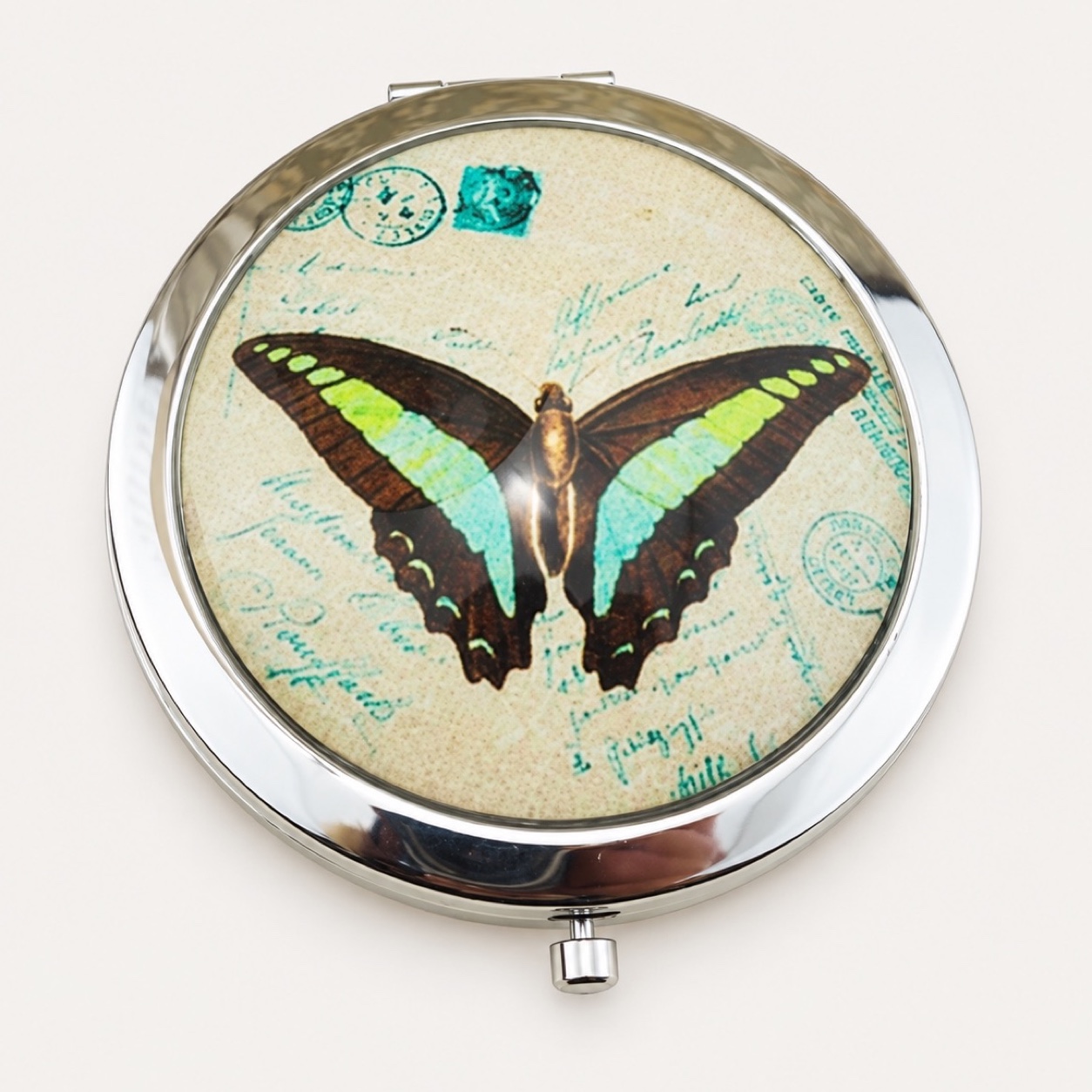 Round compact mirror with a butterfly illustration under dome glass