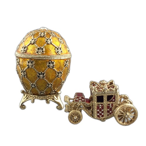 Yellow crystal lattice egg with a miniature carriage on a white background