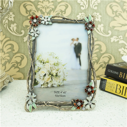 An antique-silver metal photo frame decorated with enamel wildflowers